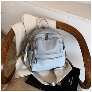 Close-up of light blue leather backpack with silver zippers and webbing straps