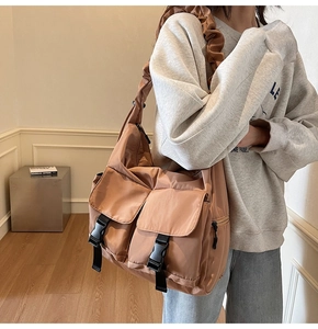 Detail of orange nylon tote bag with two buckle pockets and stylish pleated shoulder strap