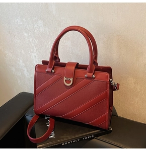 Dettaglio della borsa tote rosso scuro in pelle martellata con fibbia dorata su rivista