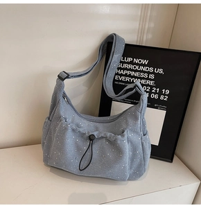Detail view of light blue corduroy crossbody bag with drawstring pockets and silver spots