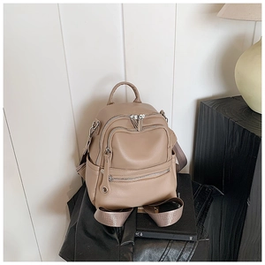 Close-up of khaki faux leather backpack with triple zipper pockets and fabric straps