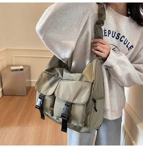 Detail of army green nylon tote bag with wide pleated strap and double front pockets