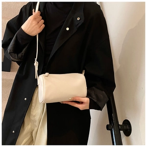 Détail du sac polochon crème montrant le grain de cuir fin et la bandoulière sur mannequin