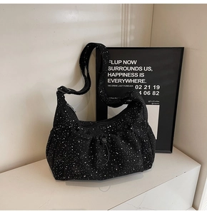 Detail of black corduroy tote bag with white splatter pattern and adjustable strap