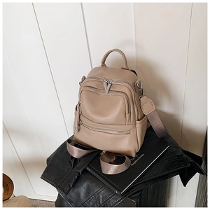 Detail of khaki pebbled leather backpack with silver zippers and wide textile strap
