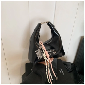 Détail du sac à main noir brillant en demi-lune avec charms de raquette de tennis