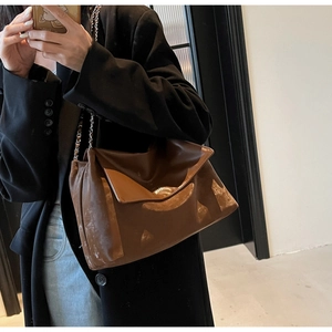 Mirror selfie showing a brown glossy leather shoulder bag with metallic chain strap