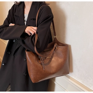 Detail der dunkelbraunen Leder-Shopper-Tasche mit Schultergurt und seitlichen Kordeln