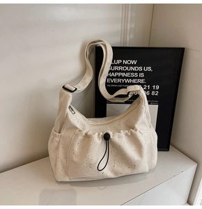 Close-up of cream nylon crossbody bag featuring silver sequins and adjustable wide strap