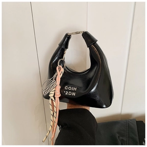 Détail du sac hobo en cuir verni noir avec logo en métal argenté et pendentif tressé