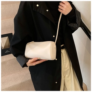 Détail du sac cylindre en cuir grainé blanc cassé porté par un mannequin ici