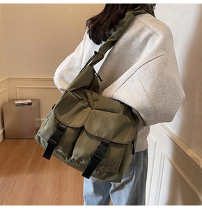 Detail showing the large olive green canvas tote bag with functional buckle pockets