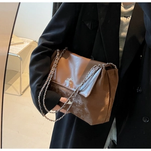 Close-up of brown patchwork leather tote bag with metal chain strap and logo detail