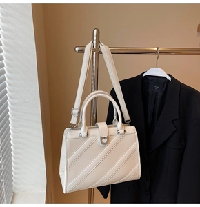 Dettaglio della borsa in ecopelle bianco sporco con cuciture a righe e fibbia a ferro di cavallo