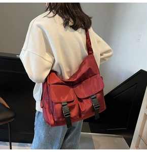 Detail of red nylon tote bag with two large flap pockets and black buckles