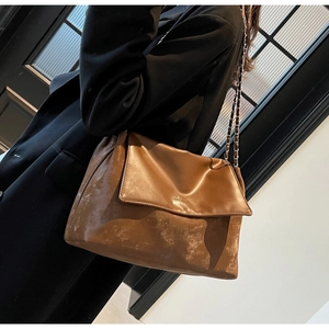 Detail of vintage brown leather tote bag with braided chain strap and logo flap
