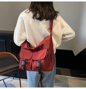 Detailed side view of burgundy nylon messenger bag with buckle pockets and wide strap