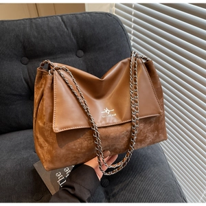 Close-up of brown patchwork leather bag with silver chain strap and brand logo