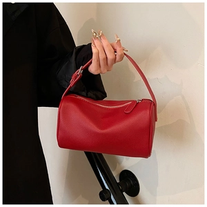 Détail du sac polochon en cuir rouge grainé avec bandoulière et fermeture éclair