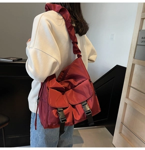 Detail of burgundy nylon tote bag with pleated strap and dual front buckle pockets