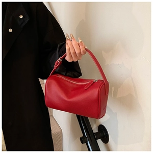 Gros plan détaillé d'un sac à main cylindrique rouge avec texture grainée et poignée