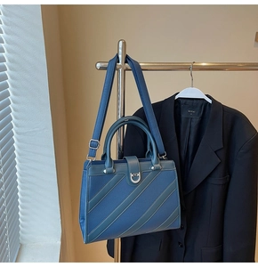 Dettaglio borsa a mano blu scuro in pelle martellata con strisce e fibbia argento