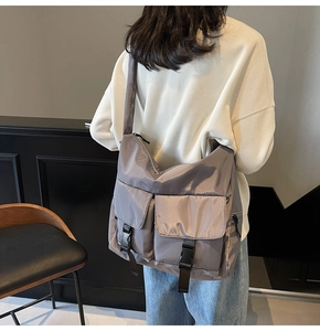 Detail of a large dark grey nylon tote bag with dual front pockets and buckle closures