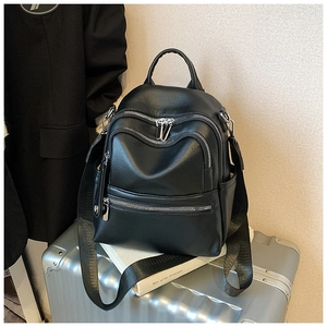 Detail of black pebbled PU leather backpack with zippers on a silver suitcase