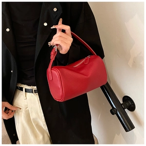 Détail du sac boston en cuir rouge vif avec texture grainée et poignées élégantes de mode
