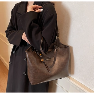 Detail der dunkelbraunen Leder-Tote-Bag mit Seitenansicht und Logo am Modell
