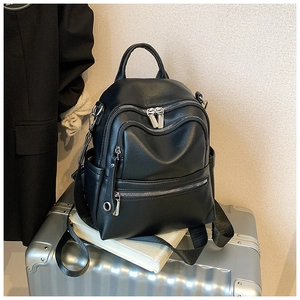 Detail of a black leather backpack with silver zippers and textured pebbled finish