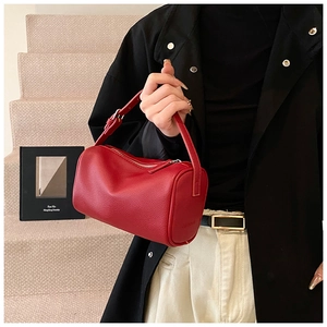 Gros plan d'un sac cylindrique en cuir grainé rouge avec fermeture éclair argentée