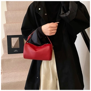 Détail d'un sac Boston cylindrique rouge vif avec texture en cuir grainé et bandoulière