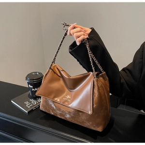 Close-up of brown patchwork tote bag with chain strap and elegant brand logo