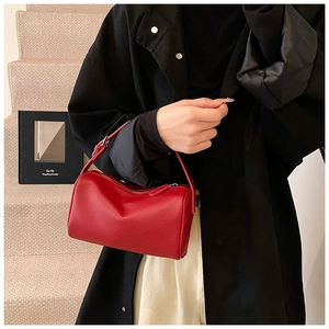 Détail du sac à main cylindrique en cuir rouge avec fermeture éclair et bandoulière