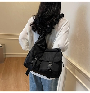 Detail of black nylon crossbody bag featuring ruffled shoulder strap and buckle pockets