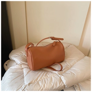 Vue détaillée du cuir grainé marron-orange et de la fermeture éclair métallique du sac oreiller