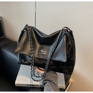 Close-up of a black leather tote featuring silver chain strap and brand logo detail