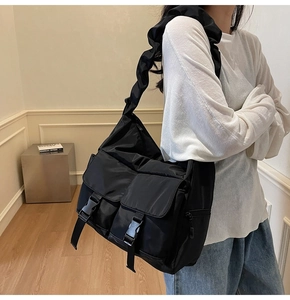 Detail of black nylon tote bag featuring ruffled strap and double buckle pockets