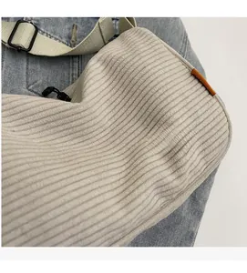 Detail der Cordstoff-Textur und des verstellbaren grünen Schultergurts der Tasche