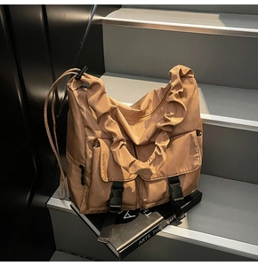 Detail of caramel nylon tote bag showing pleated handles and buckle pockets texture