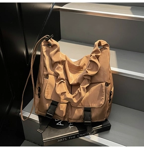 Detail of tan nylon tote bag showing ruched shoulder strap and functional buckle pockets