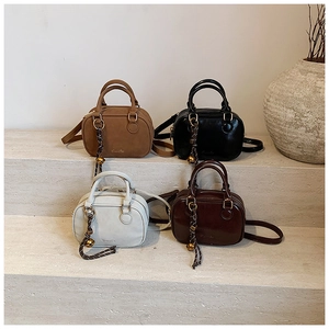 Detail view of mini Boston pillow bags in khaki, black, white, and brown colors