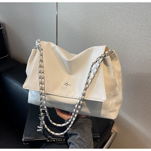 Detailed view of cream-colored leather tote bag with woven chain strap and logo