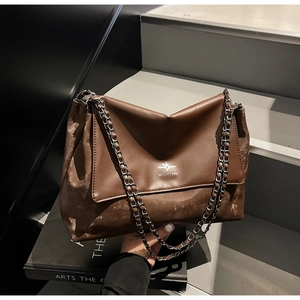 Detail of coffee brown chain shoulder bag with white logo print and silver metal strap