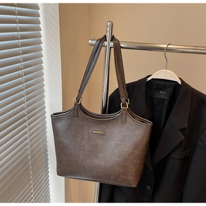 Detailansicht einer großen braunen Tote-Bag aus strukturiertem Kunstleder mit Goldringen