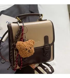 Detail eines Retro-Lederrucksacks mit Farblock-Design, Bärenanhänger und Schnallen