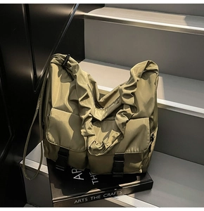 Close-up of olive green nylon tote bag featuring ruffled strap and dual buckle pockets