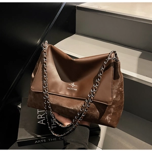 Detail of vintage brown leather and suede tote bag with silver chain and brand logo