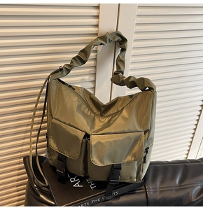 Detail of army green nylon hobo bag featuring cargo pockets and pleated shoulder strap